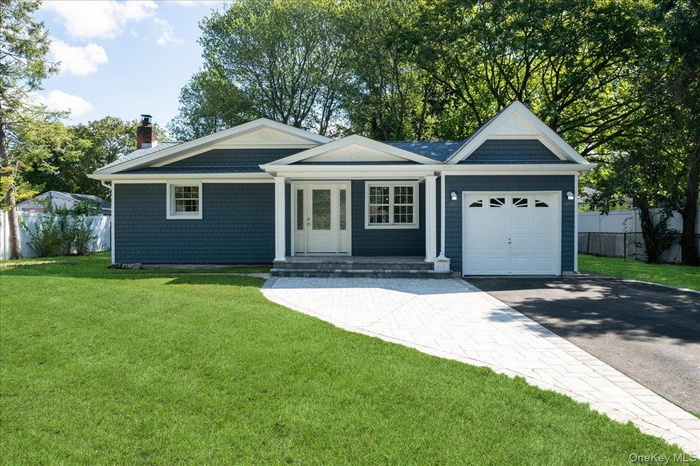 Ranch-style home featuring an attached garage, driveway, and a chimney