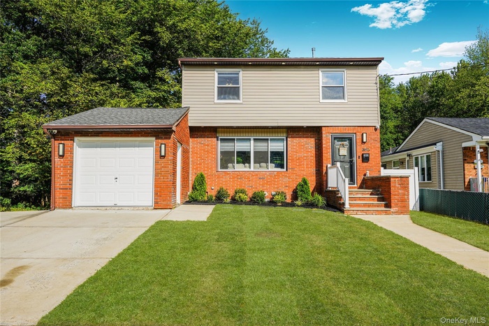Colonial house featuring brick siding, driveway, and a garage