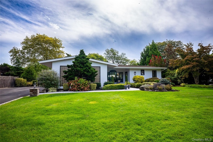 Mid-century modern home featuring a front yard and stucco siding