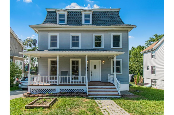 Victorian home featuring covered porch, a front lawn, and mansard roof