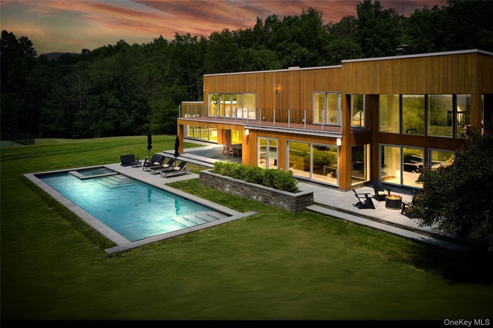 Back of house featuring a patio, a yard, and a pool with connected hot tub