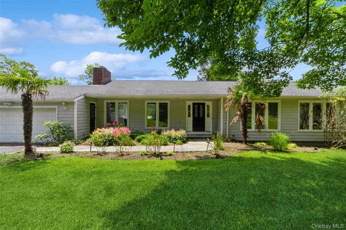Ranch-style house featuring an attached garage, a chimney, a front yard, and a shingled roof