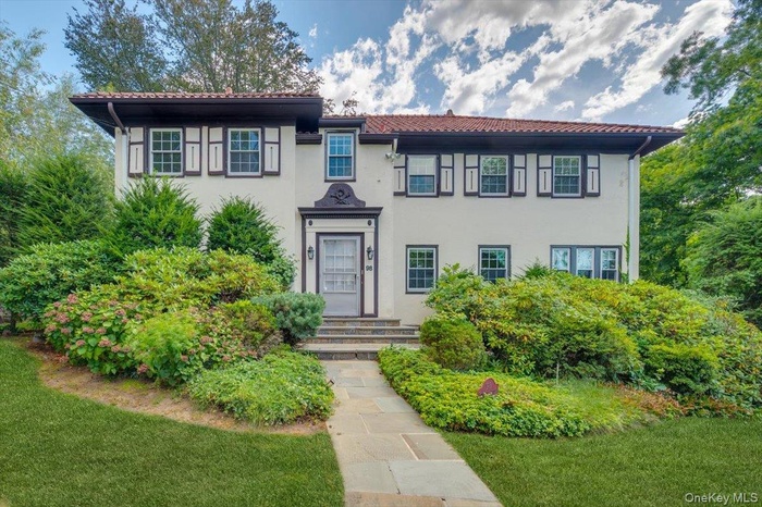 Mediterranean / spanish house with stucco siding, a tiled roof, and a front yard