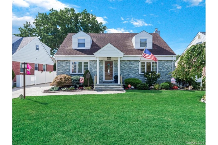 Cape house with portico, stone facade and custom pavers.