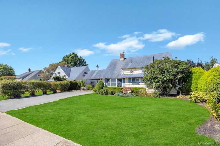 View of front of house featuring a front yard, a chimney, and driveway