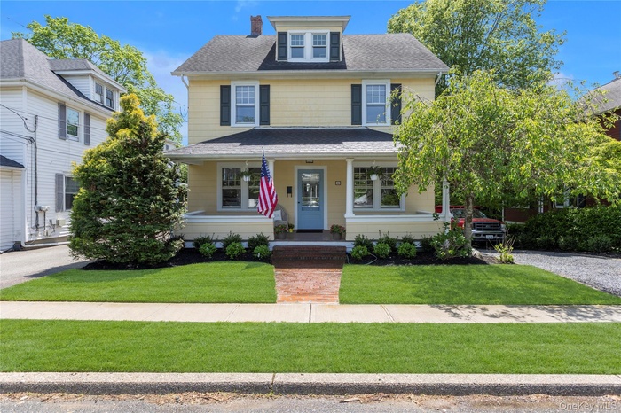 Victorian style home featuring a porch, a front yard, a shingled roof, and a chimney