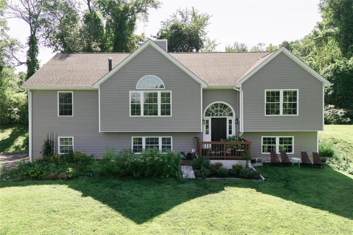 Rear view of house with a yard, roof with shingles, and a deck