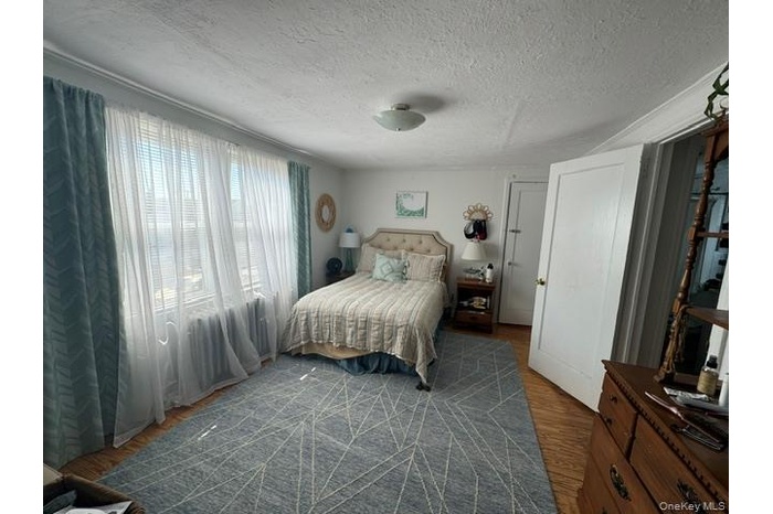 Bedroom with a textured ceiling and dark wood-type flooring