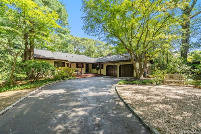 View of front of house with garage, asphalt driveway, a chimney, and roof with shingles