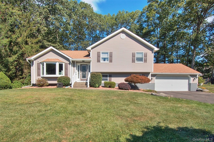 Split level home with a front lawn, driveway, and an attached garage
