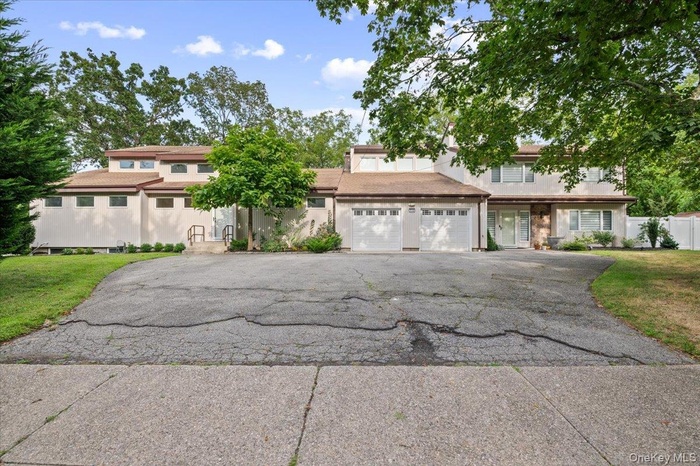 View of front of property with driveway, a front yard, a garage, and stucco siding