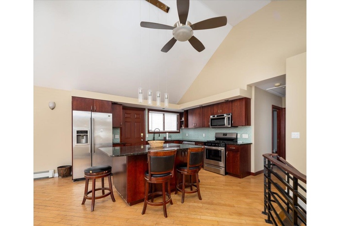 Kitchen featuring a center island, a breakfast bar, baseboard heating, light wood-style flooring, and stainless steel appliances