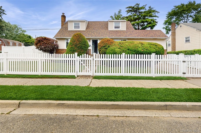 View of front of home with a fenced front yard, a shingled roof, a chimney, a gate, and brick siding