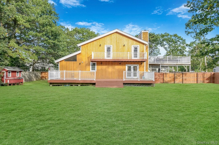 Rear view of property with a wooden deck, a fenced backyard, french doors, and a chimney