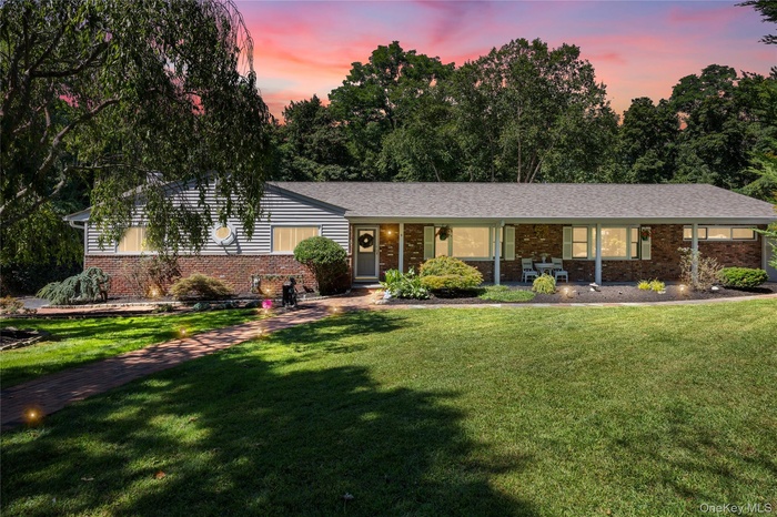 Single story home featuring a front lawn, covered porch, and brick siding