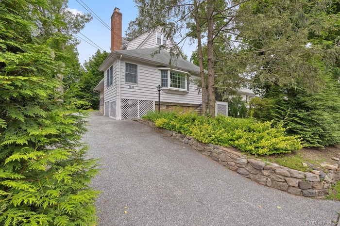 View of property exterior with a chimney and asphalt driveway