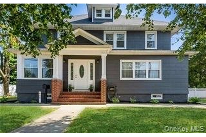 American foursquare style home with a front lawn and covered porch