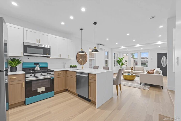 Kitchen with a peninsula, appliances with stainless steel finishes, recessed lighting, light wood finished floors, and white cabinets