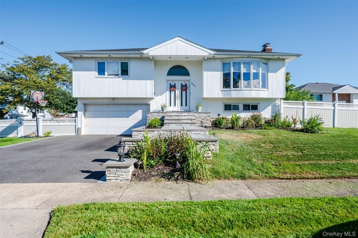 Split foyer home with a garage, asphalt driveway, a chimney, and roof with shingles