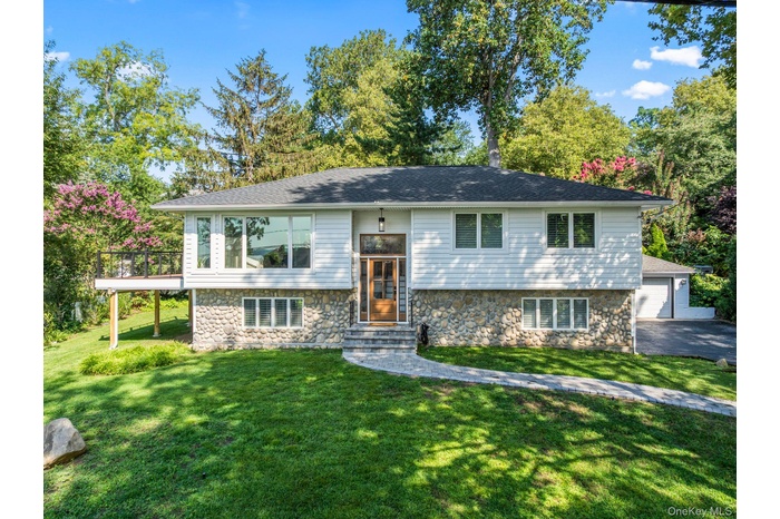 Split foyer home featuring stone siding, a front yard, a garage, and entry steps