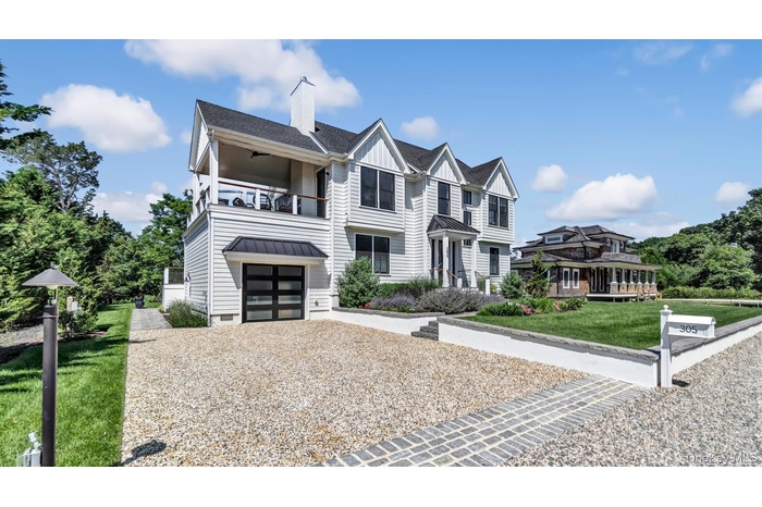 Townhome / multi-family property featuring a balcony, board and batten siding, a garage, gravel driveway, and a front yard