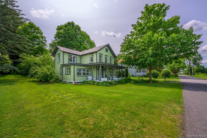 View of home's exterior featuring a porch, a lawn, and a metal roof