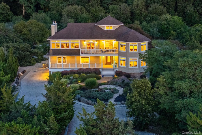 Back of property with stairs, roof with shingles, a balcony, a chimney, and a wooded view