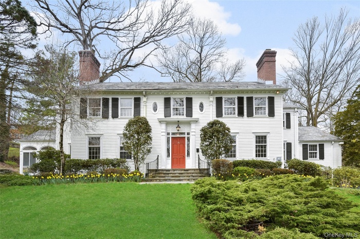 Colonial inspired home with a chimney and a front lawn