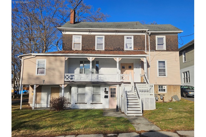 View of front of house with a front lawn, a porch, and a chimney