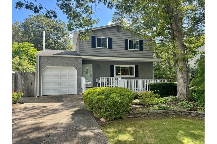 Traditional home featuring a porch, a garage, concrete driveway, stucco siding, and roof with shingles