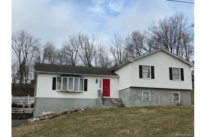 Split level home with a front lawn and fence