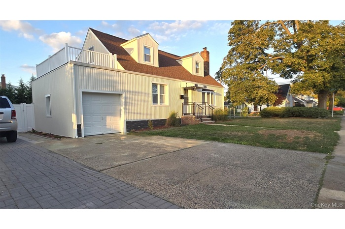 View of side of property featuring a chimney, a lawn, concrete driveway, and roof with shingles