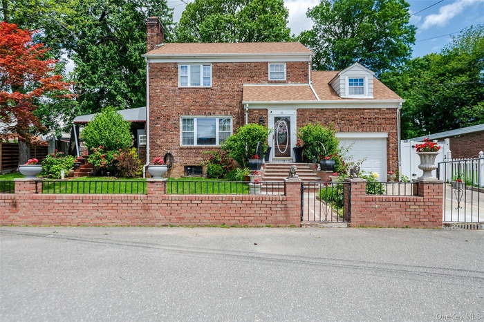 View of front of house featuring a fenced front yard, a chimney, brick siding, and an attached garage