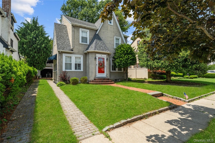 Tudor house with a shingled roof, stucco siding, and a front yard