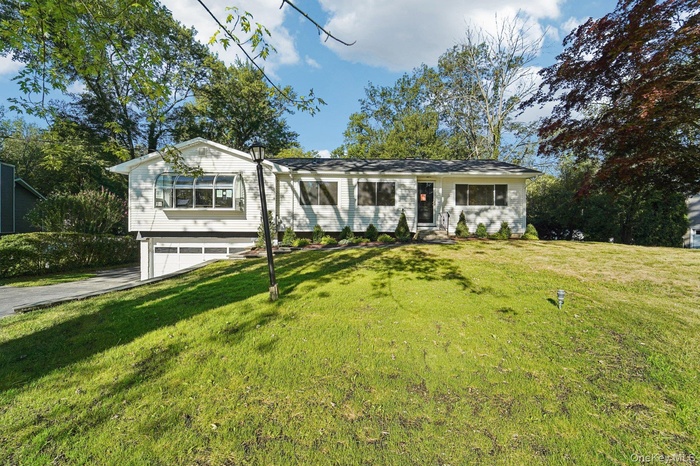 View of front of property with a front yard, an attached garage, and driveway
