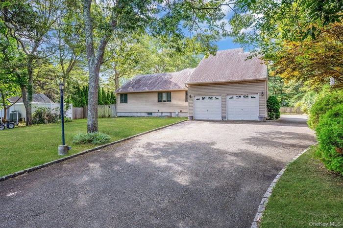View of front of house with driveway, an attached garage, and a shingled roof
