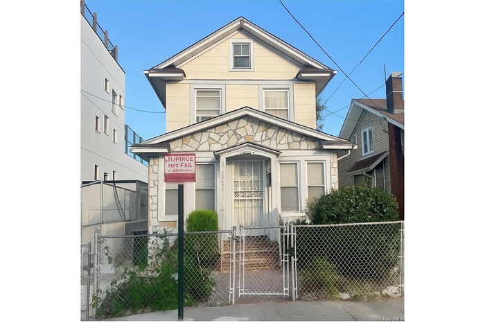 View of front of house featuring a gate, a fenced front yard, and stone siding