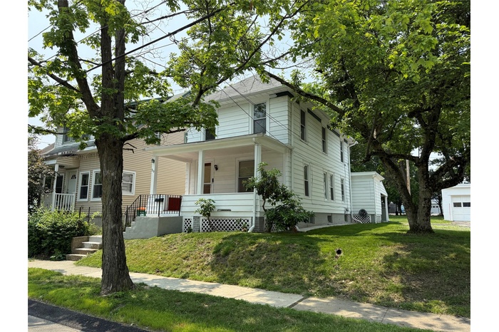Traditional style home featuring a porch and a front yard
