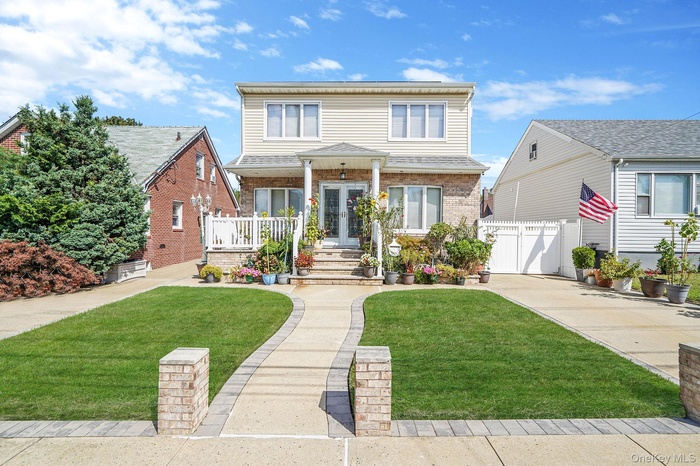 Traditional-style home with brick siding, a front yard, a porch, a gate, and concrete driveway