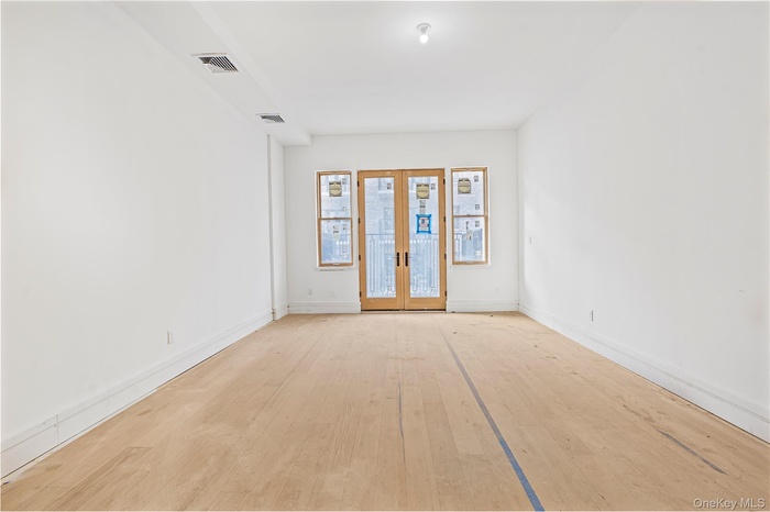 Unfurnished room featuring french doors and light wood finished floors