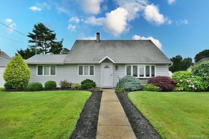 View of front of property featuring a front lawn, roof with shingles, and a chimney