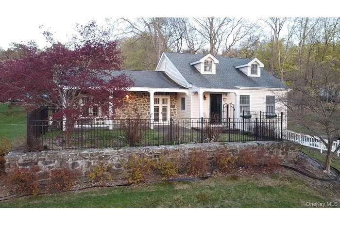 Cape cod house with stone siding and a shingled roof