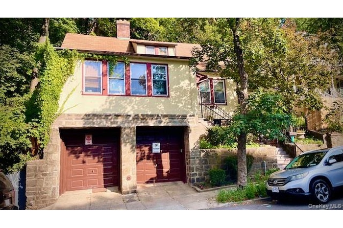 View of front of home with stucco siding, an attached garage, a chimney, and driveway