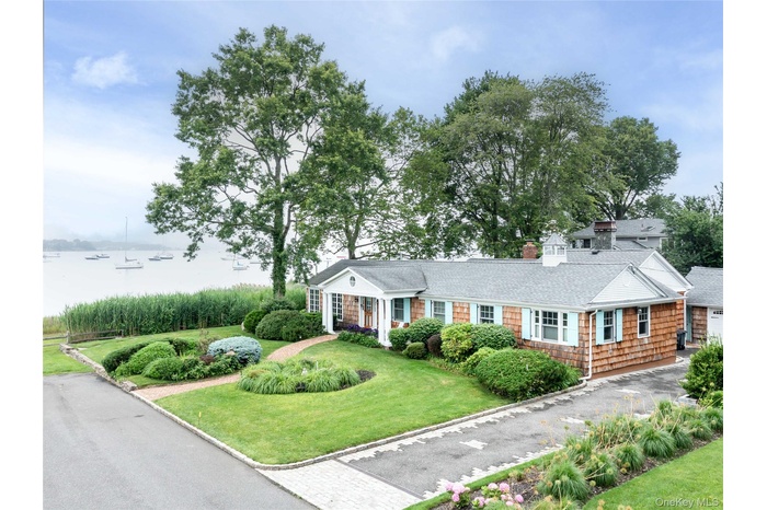 View of front of house featuring a front yard, a water view, and roof with shingles
