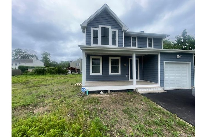 View of front of property with a porch, an attached garage, and asphalt driveway