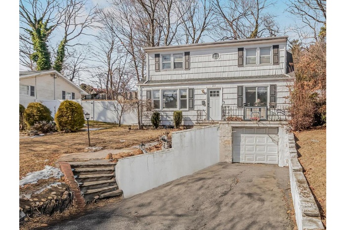 View of front of house with an attached garage, fence, and driveway
