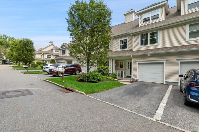 Multi unit property featuring a shingled roof and driveway