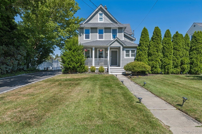 View of front of property featuring covered porch, a front lawn, and a shingled roof