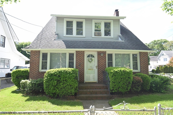 View of front of house with brick siding, a chimney, and a shingled roof
