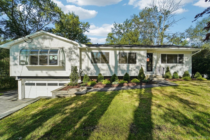 View of front facade with an attached garage, a front lawn, and driveway